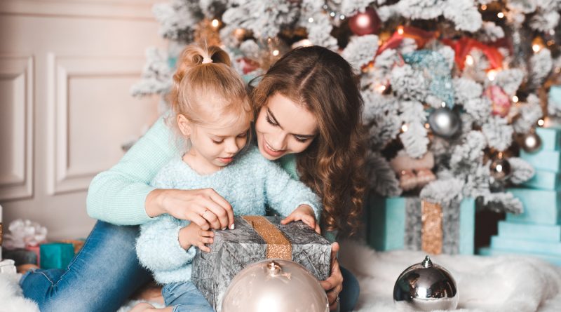 Mother and Child Joyfully Opening Gifts in front of Decorated Christmas Tree